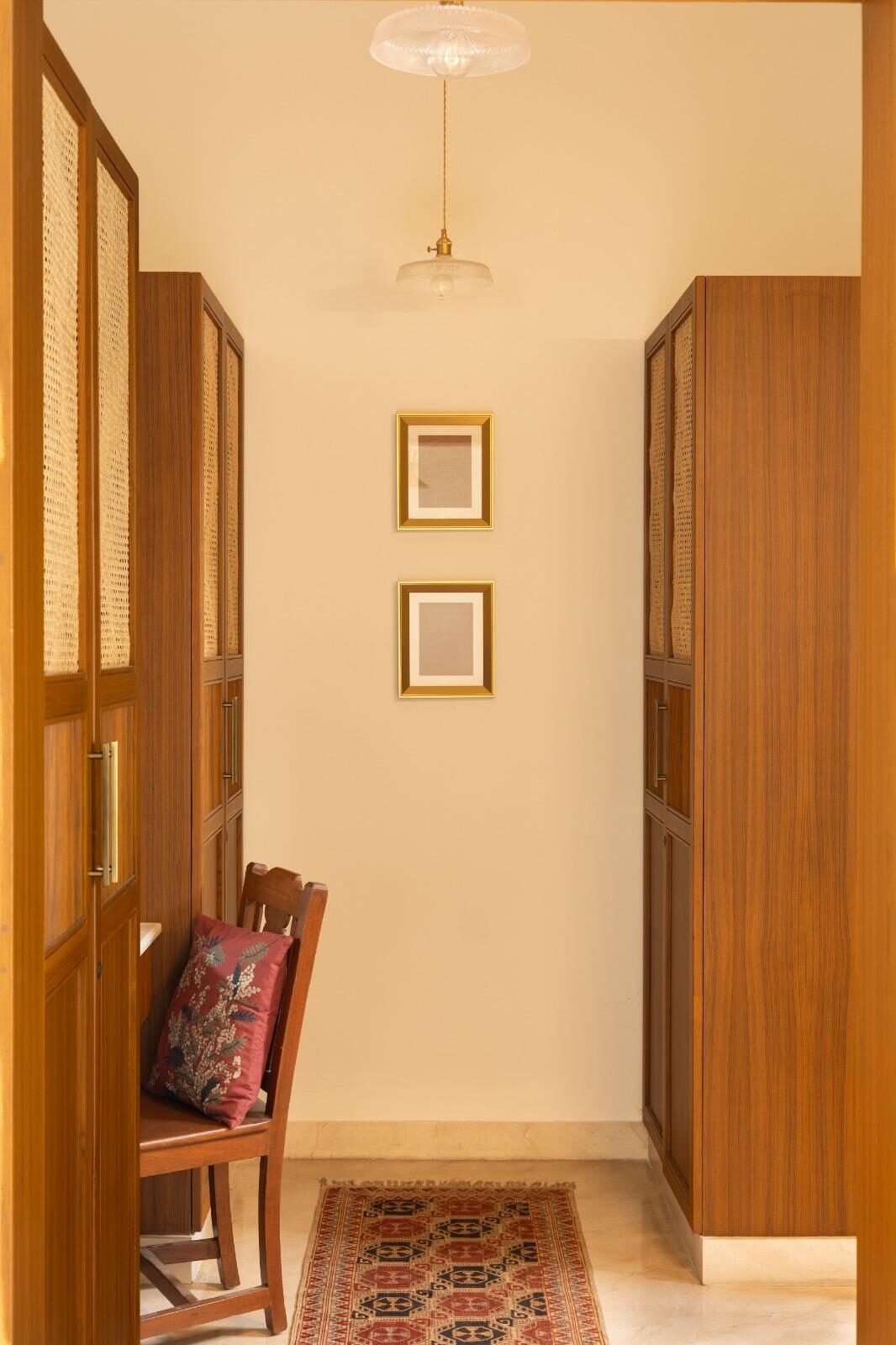Softly lit entrance hallway with teak wardrobes and a hanging pendant light